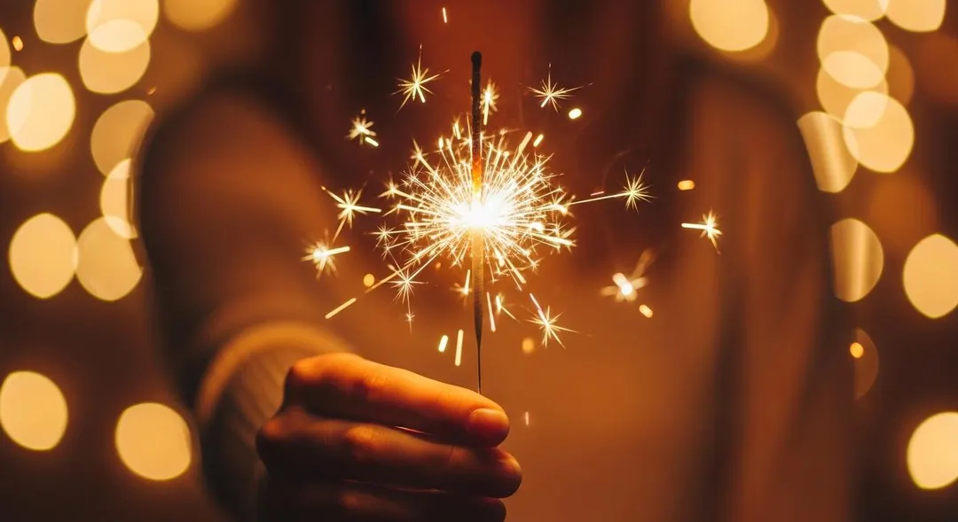 Hand holding a lit sparkler — birthday gifts by Bloom & Beyond