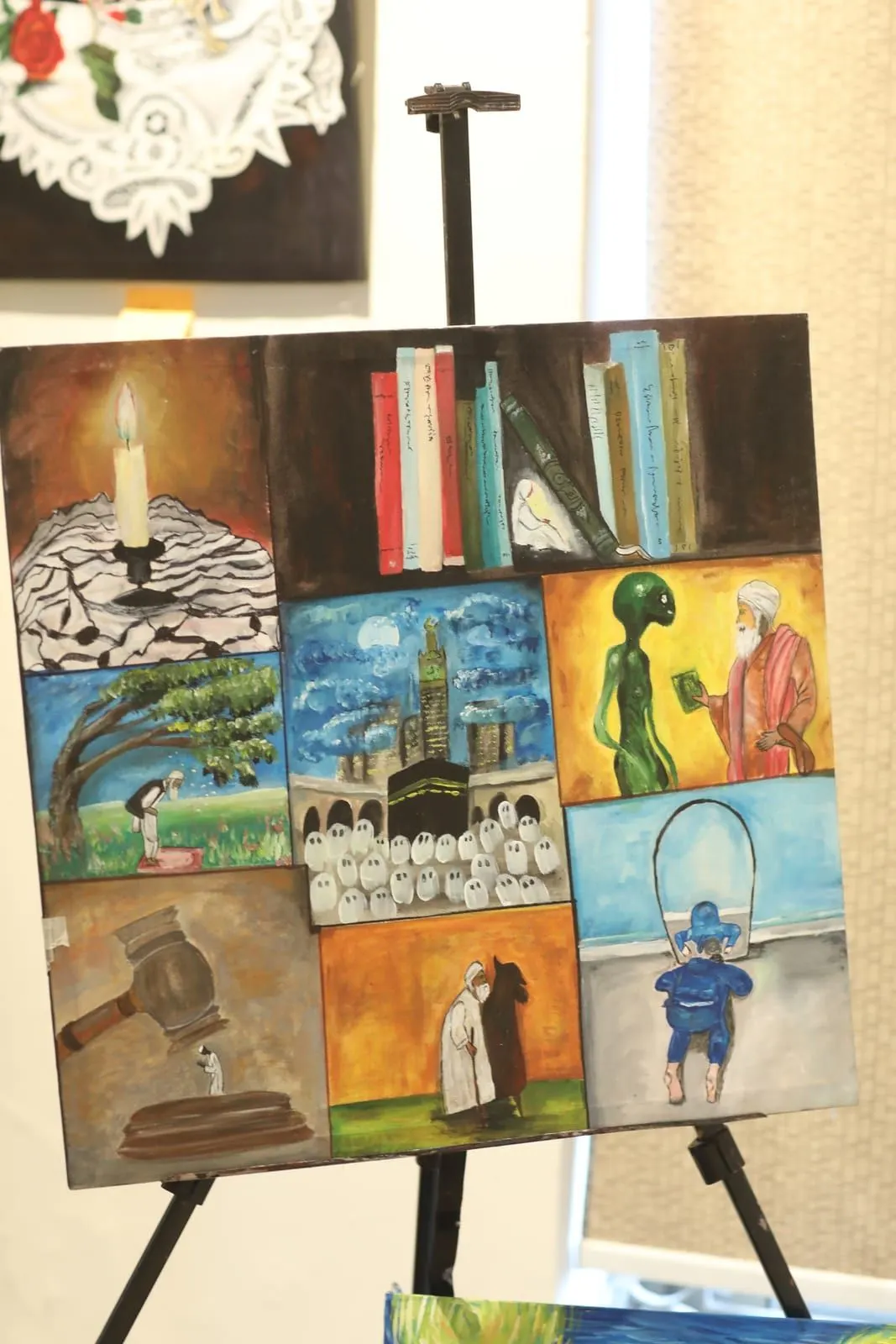 Nine-panel painting by Hafsa Imran on an easel: a candle, a bookshelf, the Kaaba with pilgrims, a man praying under a tree, a judge's gavel, an elderly man with a cane and a figure climbing into an arched opening
