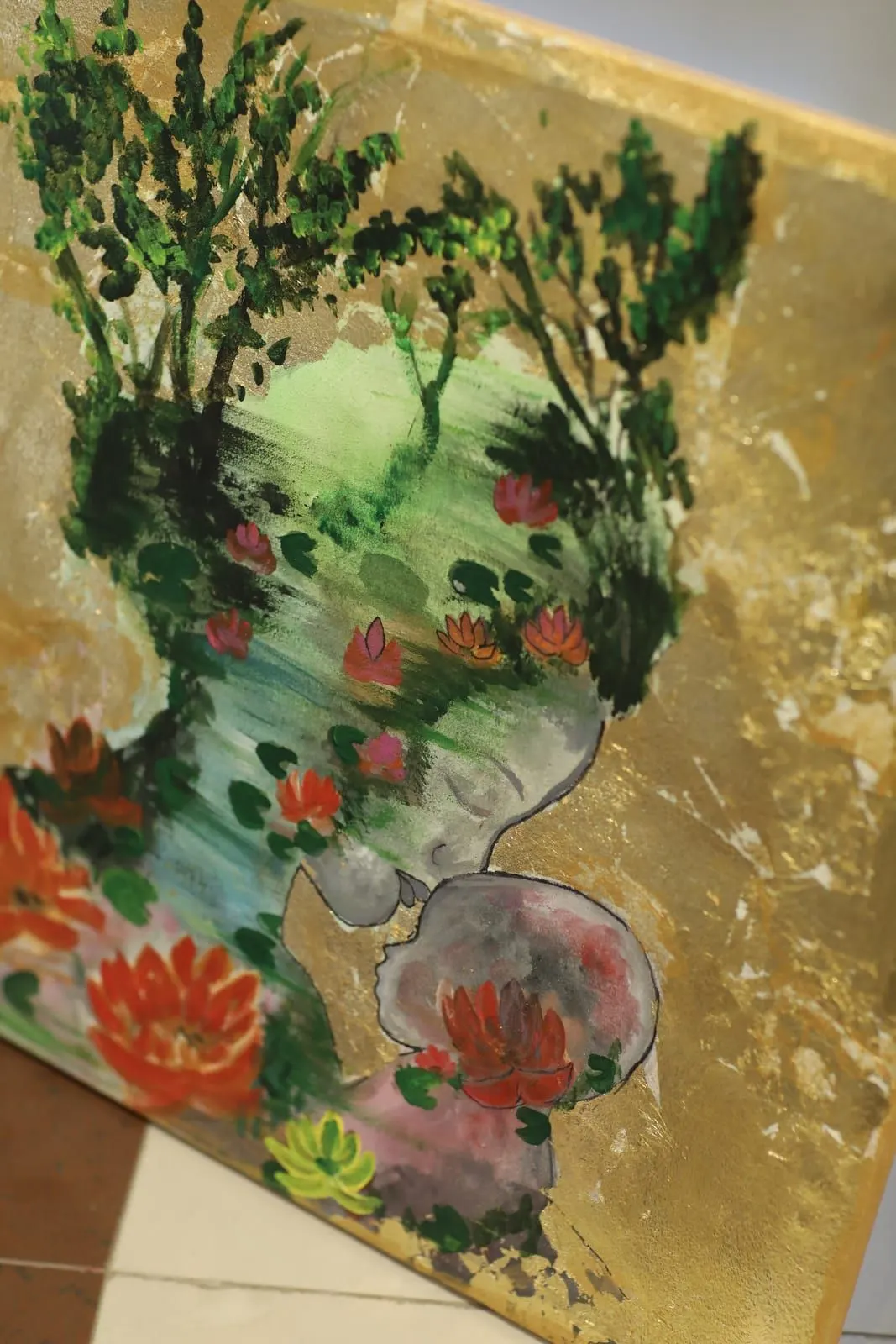 Painting by Hafsa Imran of a grey figure among red and pink lotus flowers, green water and trees, on a background of gold leaf