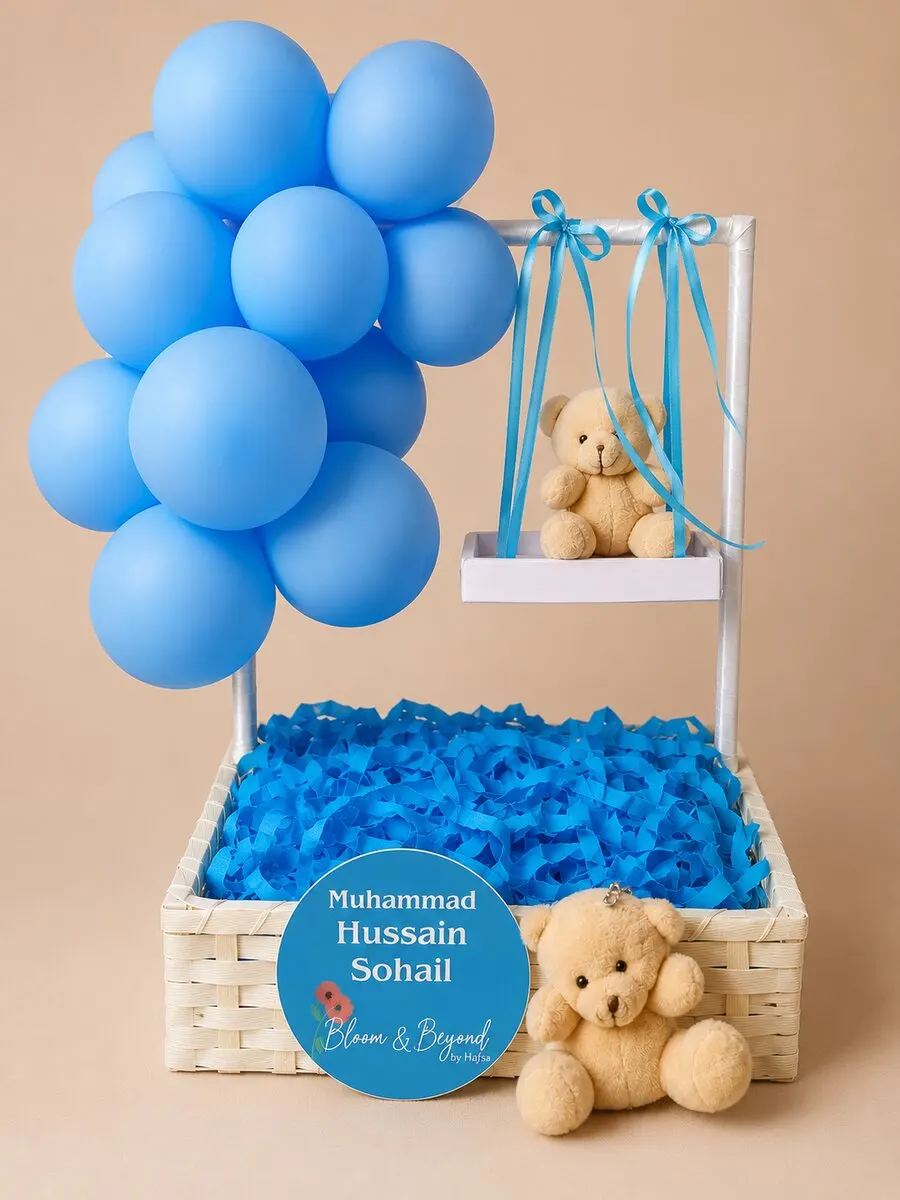 A celebration hamper for baby boys — a white wooden crate filled with sky-blue tissue, two plush teddy bears (one nestled inside — handcrafted by Bloom & Beyond in Lahore
