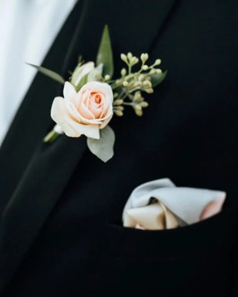 A boutonniere featuring a blush rose with baby breath and greenery, pinned on the lapel — handcrafted by Bloom & Beyond in Lahore
