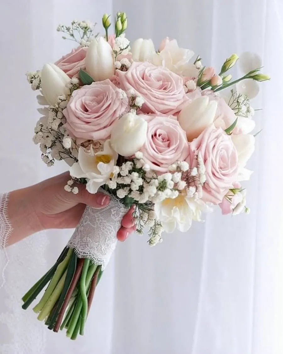 A romantic bridal bouquet with soft pink roses, white tulips, and clouds of baby breath, finished with delicate lace wrapping — handcrafted by Bloom & Beyond in Lahore
