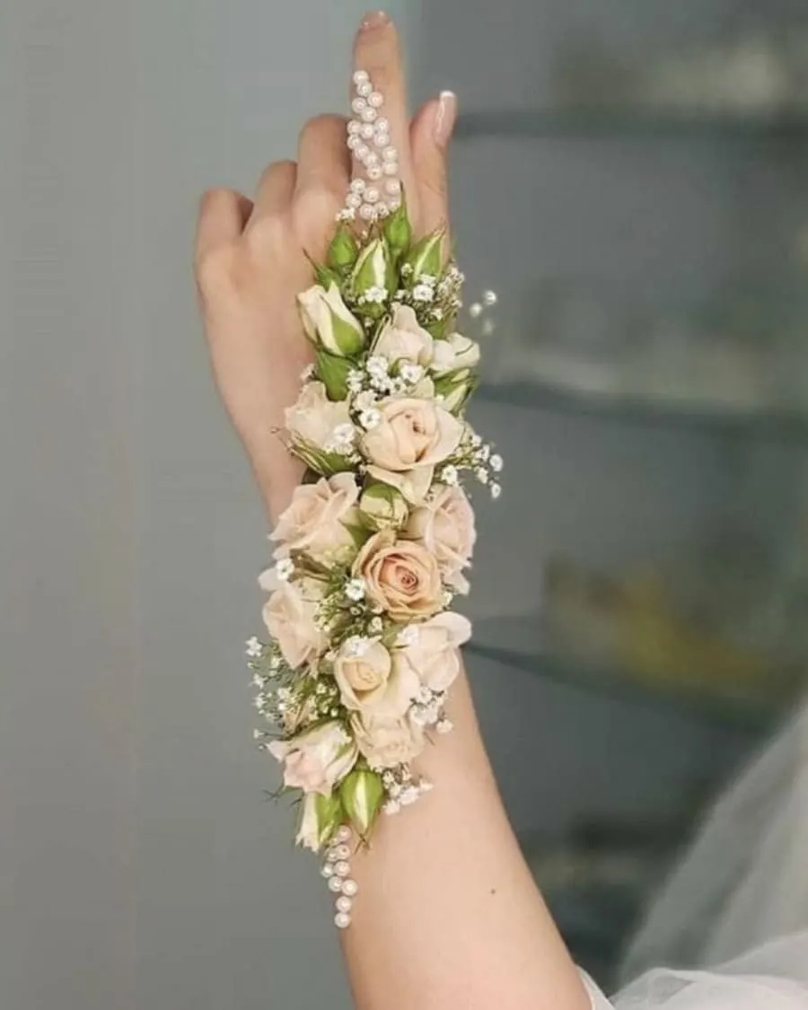 An elegant hand corsage with blush roses trailing down the hand, accented with pearls and baby breath — handcrafted by Bloom & Beyond in Lahore