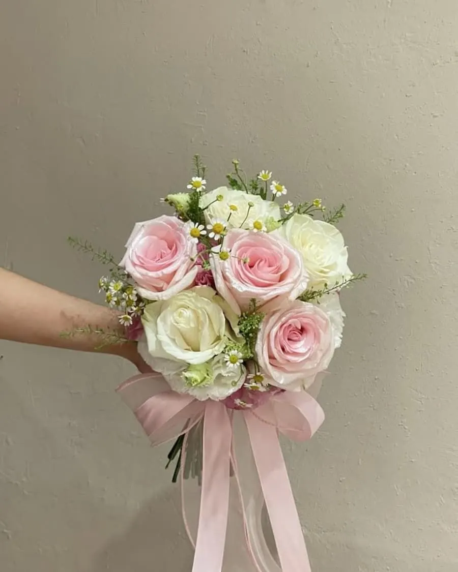 A cheerful bridesmaid bouquet mixing pink roses, white daisies, and baby breath with a ribbon finish — handcrafted by Bloom & Beyond in Lahore