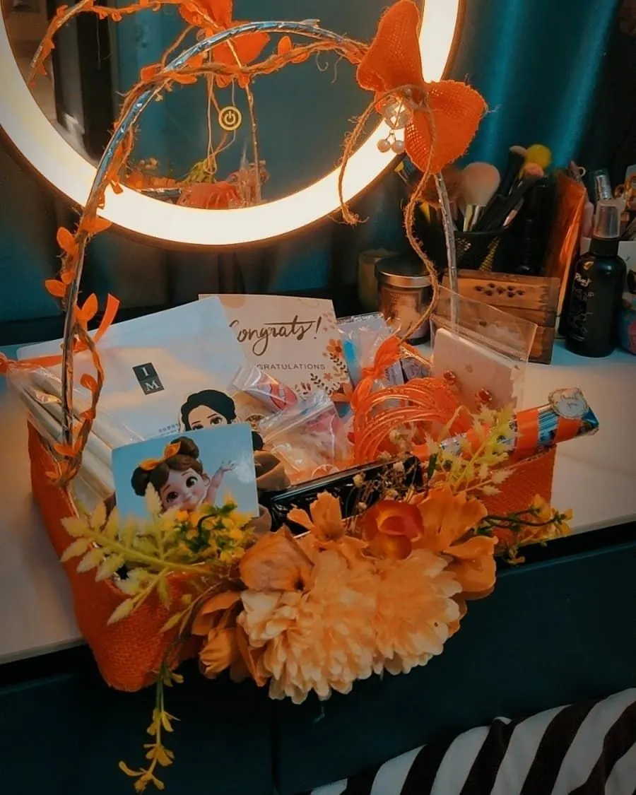 A congratulations gift basket of fresh flowers, chocolates and wrapped gifts in a woven basket — handcrafted by Bloom & Beyond in Lahore