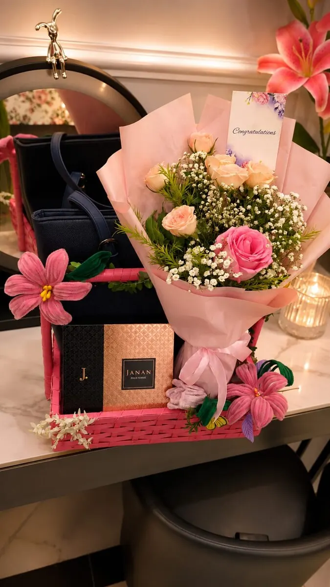 A deep pink presentation box with a hand-tied bouquet, a boxed fragrance, a handbag and a congratulations card — handcrafted by Bloom & Beyond in Lahore