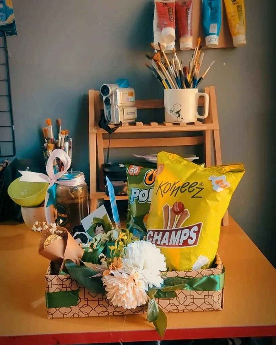 Kids snack gift basket — crisps, drinks and a mini flower bouquet in a teal and green themed basket — handcrafted by Bloom & Beyond in Lahore