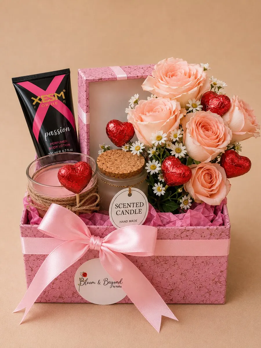 Pink gift box with flowers and chocolates — a peach rose mini bouquet with baby's breath, a scented soy candle in a glass jar, foiled red-heart chocolates and a fragrance — handcrafted by Bloom & Beyond in Lahore