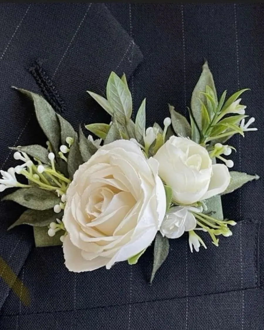 A white rose boutonniere tucked into the breast pocket like a pocket square — a modern, polished look for the dapper groom — handcrafted by Bloom & Beyond in Lahore