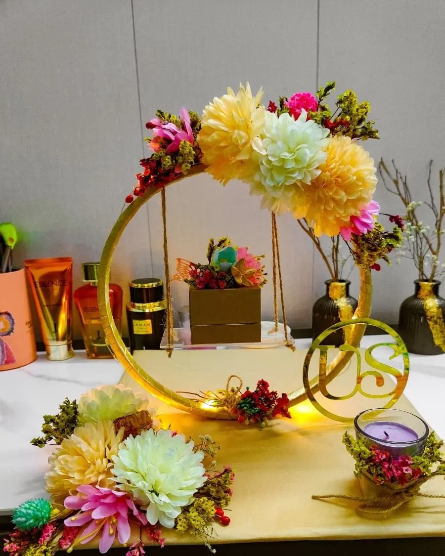 A decorated floral hoop display with candles and the couple's initials — designed to present wedding rings at the nikkah ceremony — handcrafted by Bloom & Beyond in Lahore