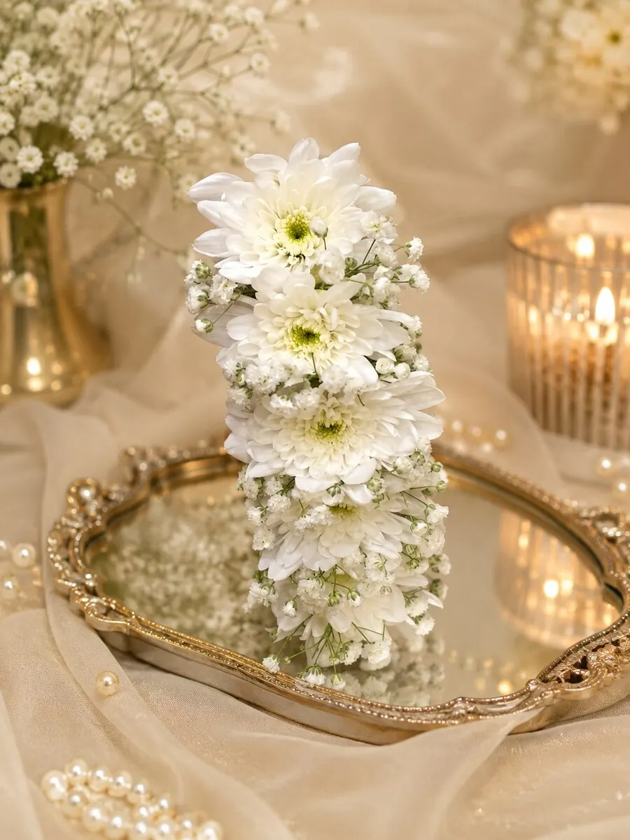 A tall column of white chrysanthemums and baby's breath standing on a gold mirrored tray — handcrafted by Bloom & Beyond in Lahore