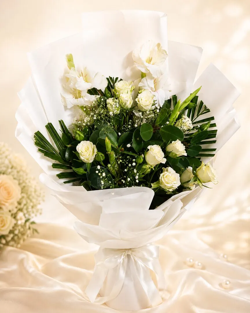 A gentle all-white bouquet of white roses and gladioli gathered with baby breath and fresh greenery — handcrafted by Bloom & Beyond in Lahore