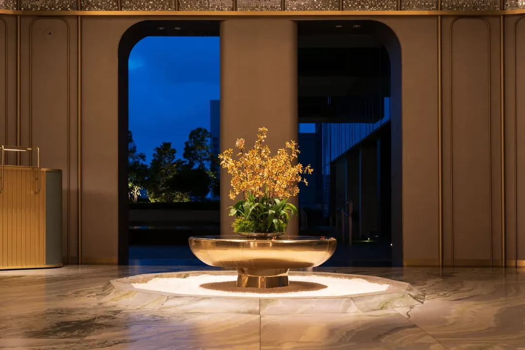 Golden orchid arrangement in a brass bowl at the centre of a marble lobby
