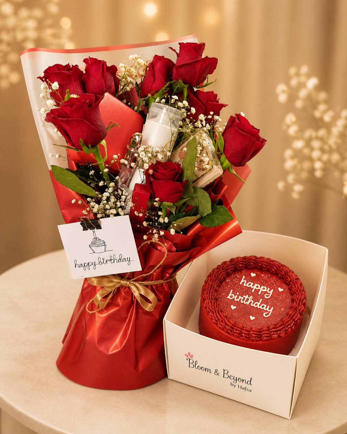 Red rose bouquet with red velvet cake — fresh red roses and baby's breath in cream-and-red paper with a gold satin ribbon — handcrafted by Bloom & Beyond in Lahore