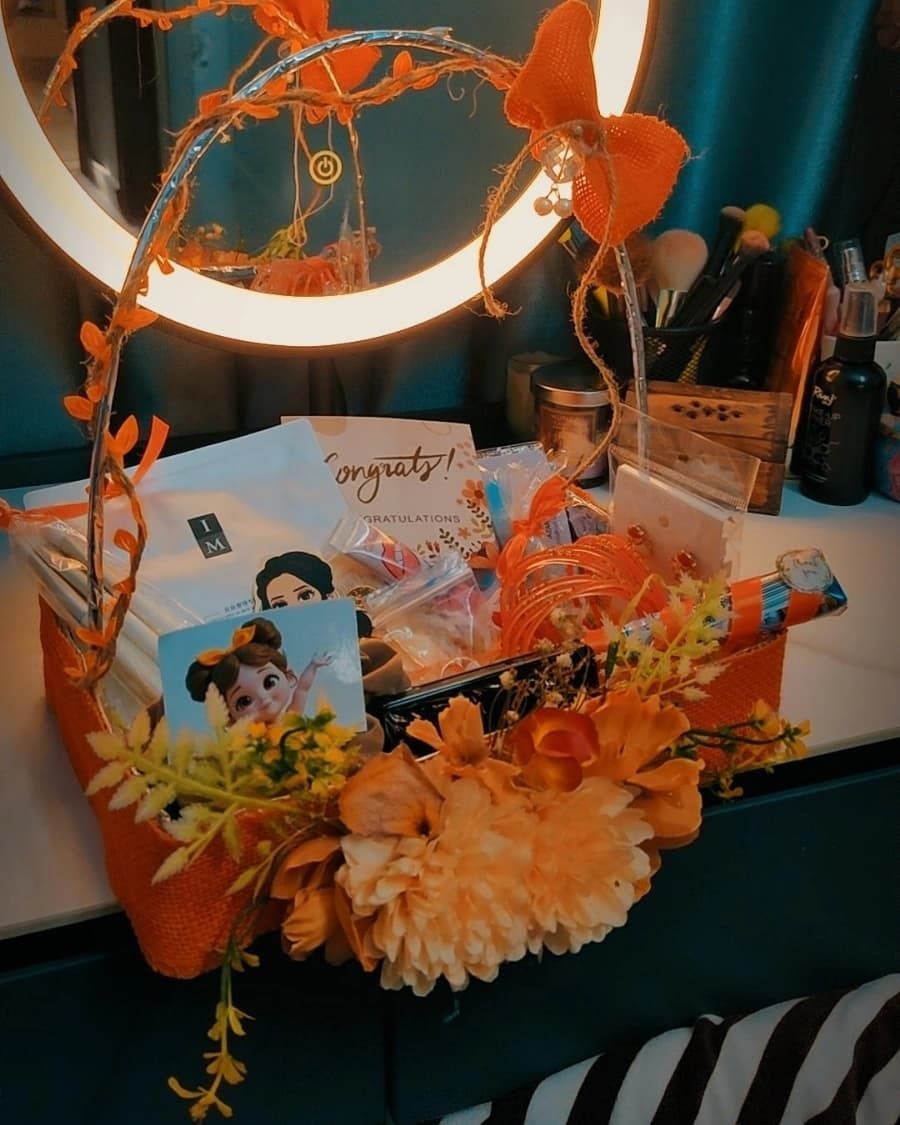 A congratulations gift basket of fresh flowers, chocolates and wrapped gifts in a woven basket — handcrafted by Bloom & Beyond in Lahore