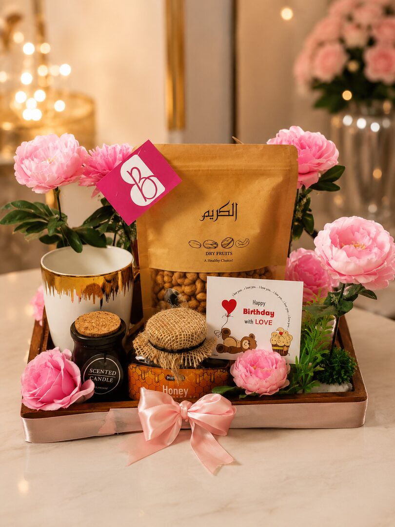 The wooden tray pairs premium dry fruits and pure honey with a gold-rimmed mug, a scented candle, fresh pink peonies — handcrafted by Bloom & Beyond in Lahore