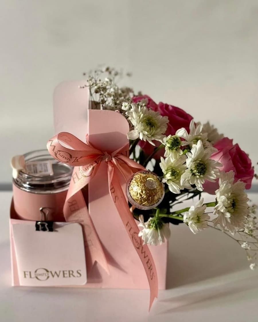 A beautiful carrier box with fresh roses, daisies, a scented candle, and Ferrero Rocher chocolates — handcrafted by Bloom & Beyond in Lahore