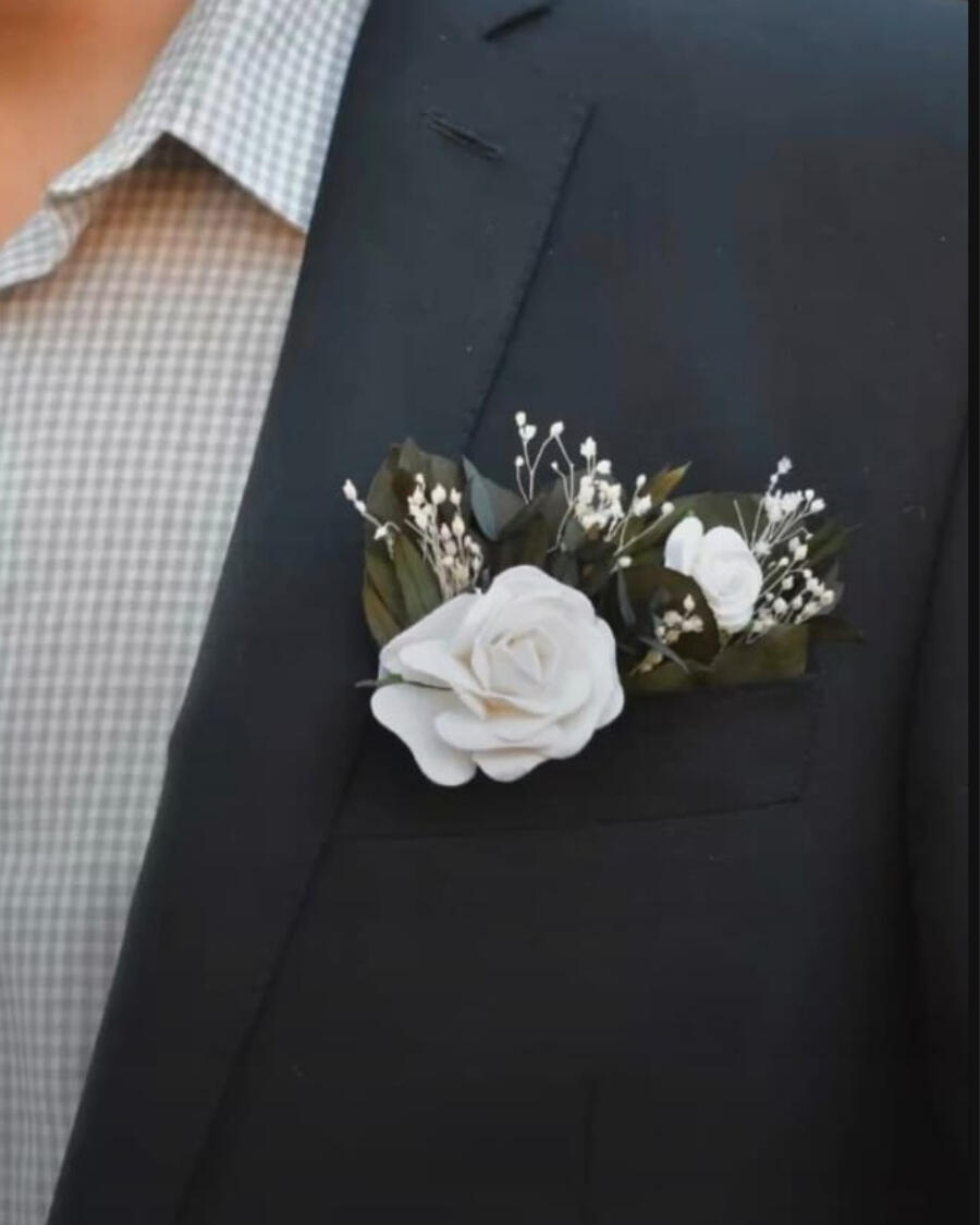 A boutonniere for the groom — a fresh white rose with baby breath and ribbon, pinned perfectly on the suit lapel for the big day — handcrafted by Bloom & Beyond in Lahore