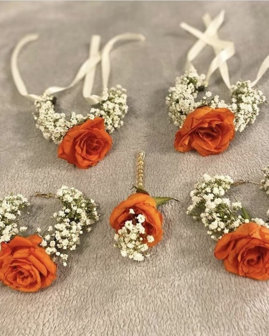 A set of three matching orange rose corsages with baby breath accents — handcrafted by Bloom & Beyond in Lahore