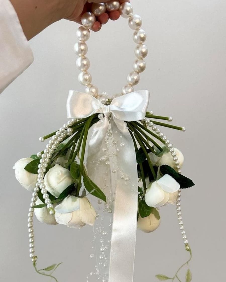 An elegant bridal bouquet of white roses accented with cascading pearl strings and a pearl-wrapped handle — handcrafted by Bloom & Beyond in Lahore