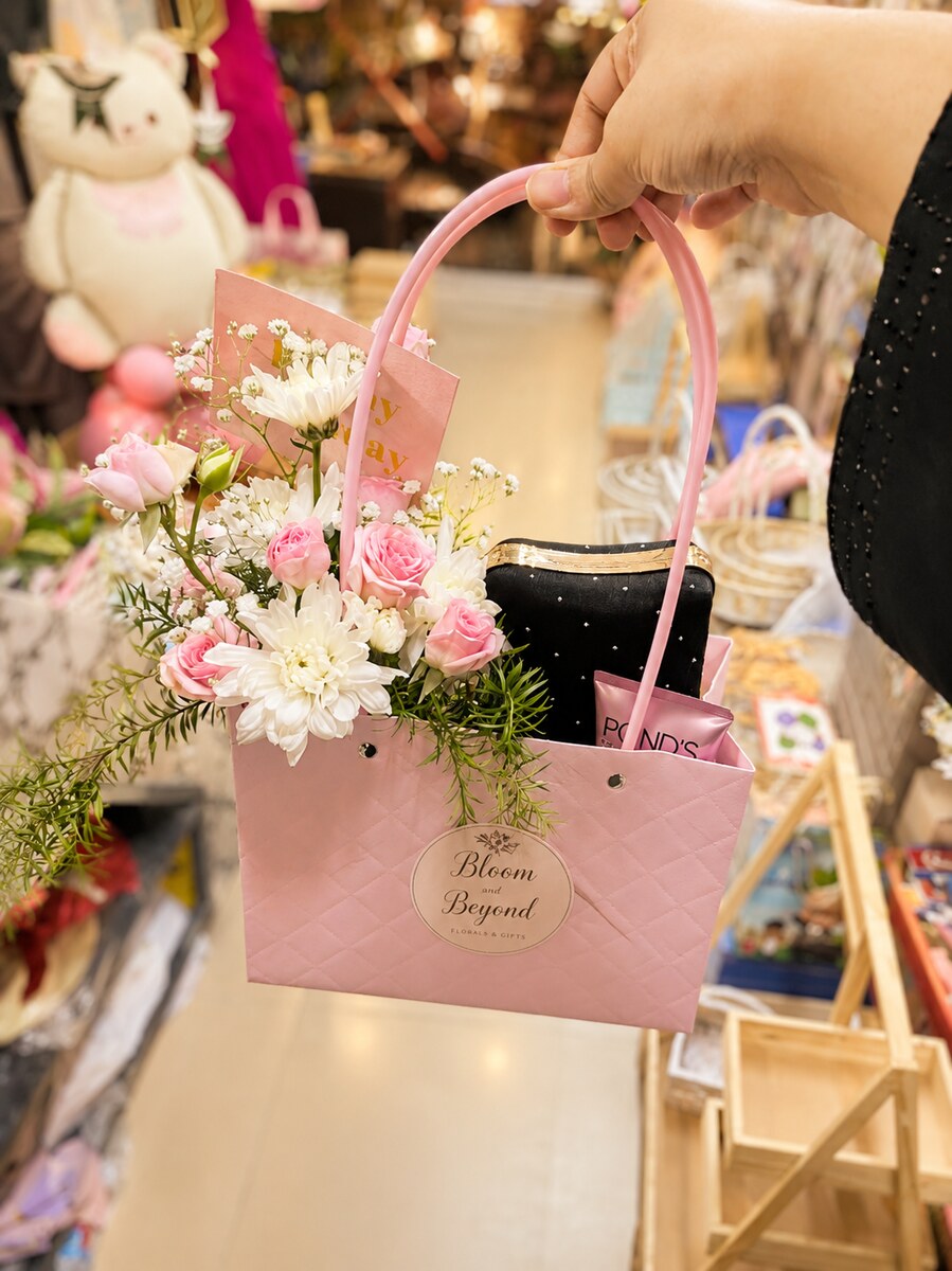 A pink Bloom and Beyond gift bag arranged with fresh white chrysanthemums and pink roses — handcrafted by Bloom & Beyond in Lahore
