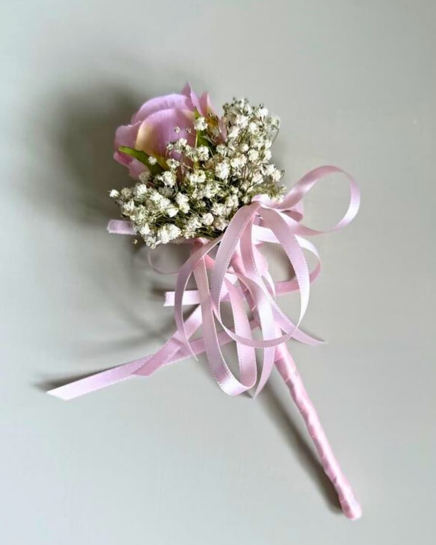 A fresh pink rose boutonniere with delicate baby breath and ribbon — handcrafted by Bloom & Beyond in Lahore