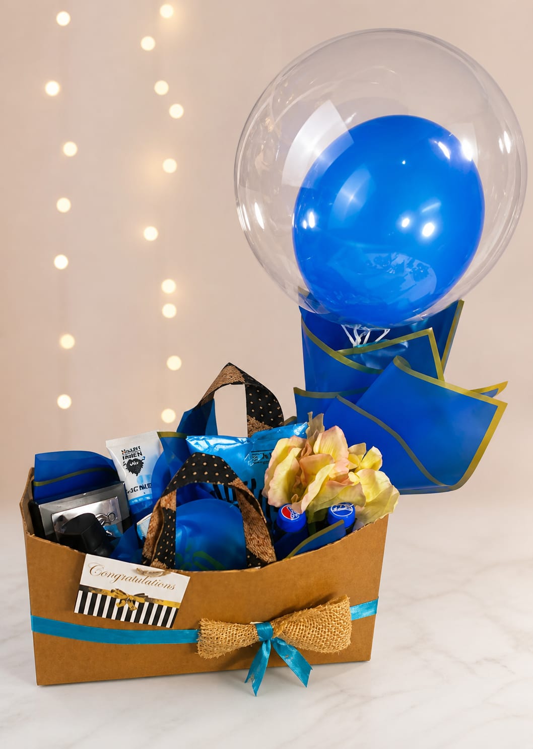 A statement-making congratulations hamper in royal blue and gold — a kraft basket layered with premium snack and chocolate hampers — handcrafted by Bloom & Beyond in Lahore