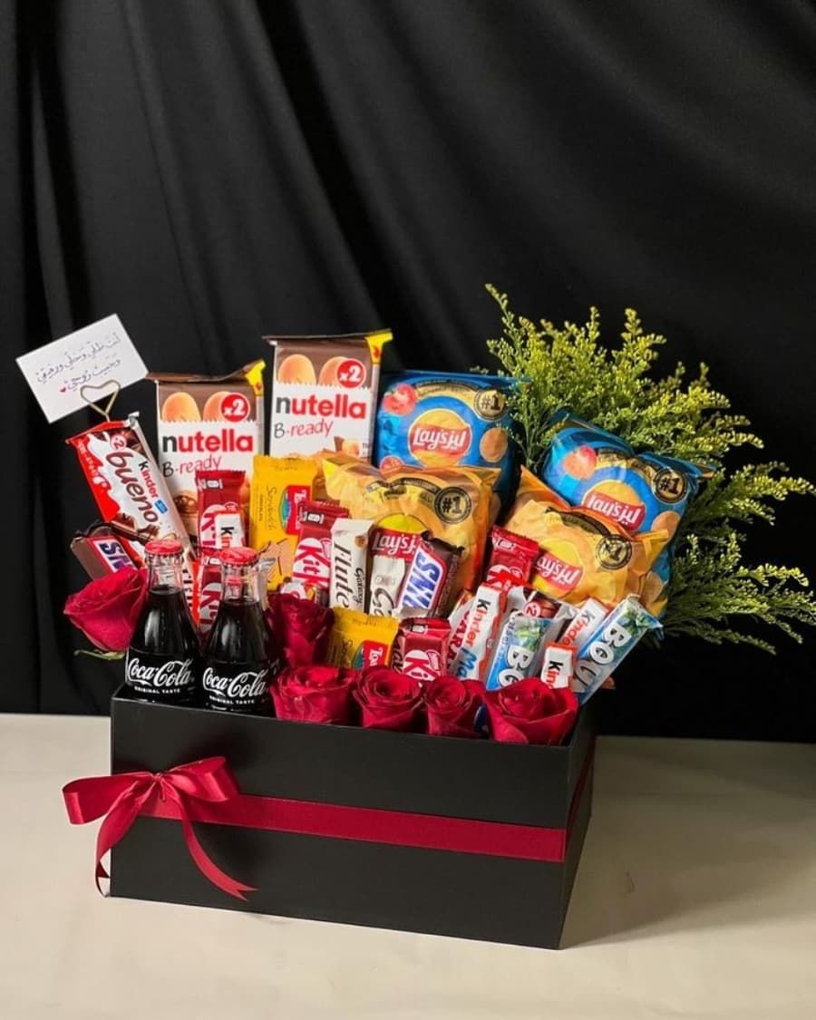 A fun-packed gift box with Nutella, Coca-Cola, KitKat, Lays chips, and fresh red roses — handcrafted by Bloom & Beyond in Lahore