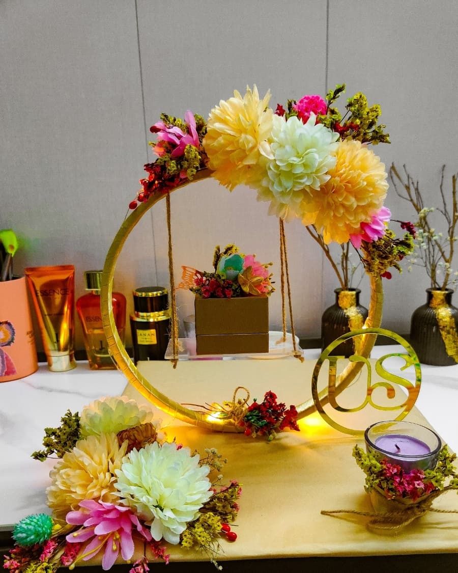 A decorated floral hoop display with candles and the couple's initials — designed to present wedding rings at the nikkah ceremony — handcrafted by Bloom & Beyond in Lahore