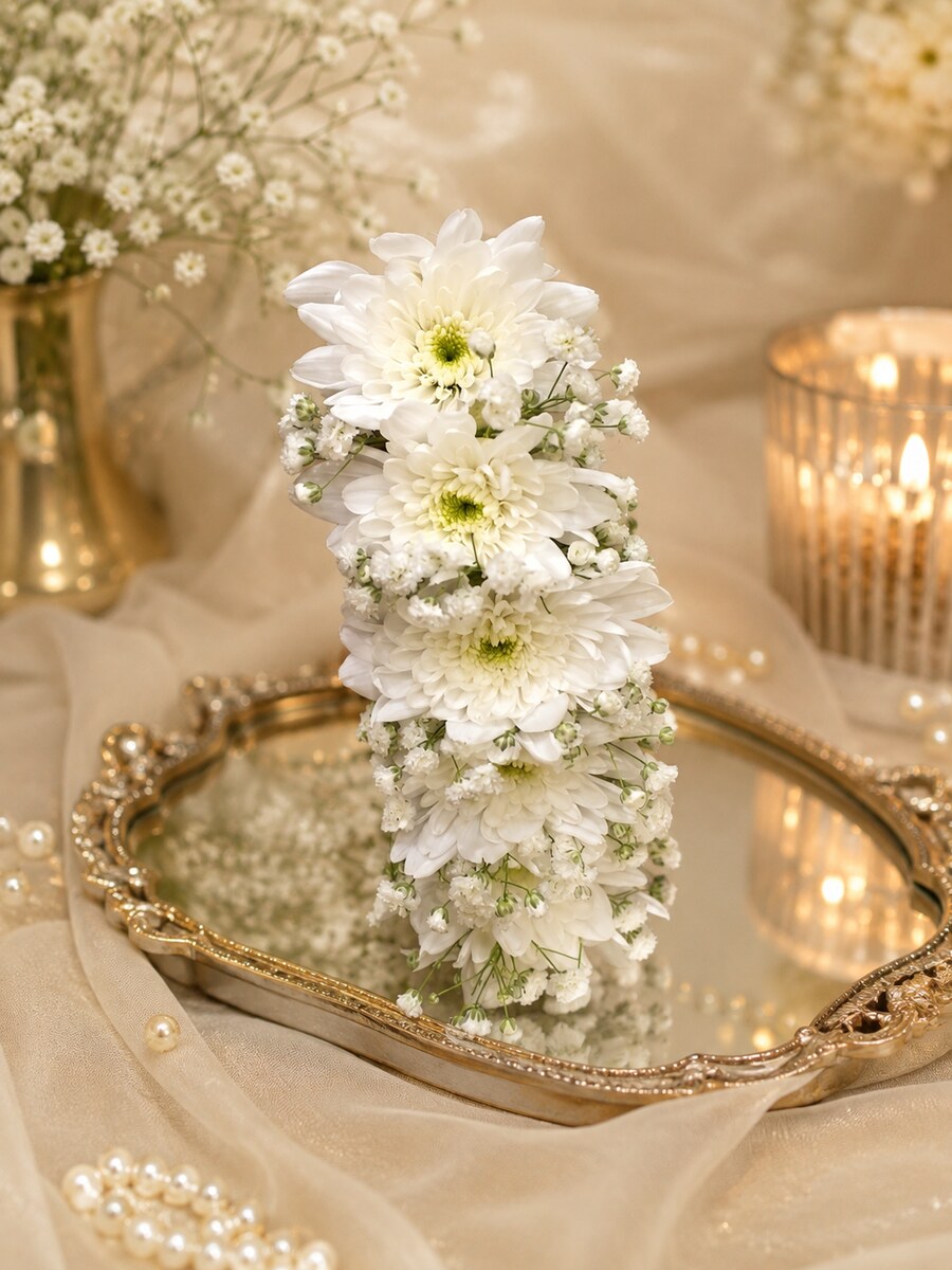 A tall column of white chrysanthemums and baby's breath standing on a gold mirrored tray — handcrafted by Bloom & Beyond in Lahore